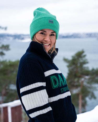 Bilde av Helene fra siden i ANN half zip genser i blå med DRYSS lue i grønn. 100% merinoull.