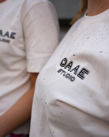 Nærbilde av Alex t-skjorte i hvit og DAAE Studio logoen.
