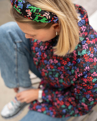 En modell som har på seg Elisabeth hårbøyle med røde, grønne, blå og rosa blomster på. Hårbøylen er laget av perler.